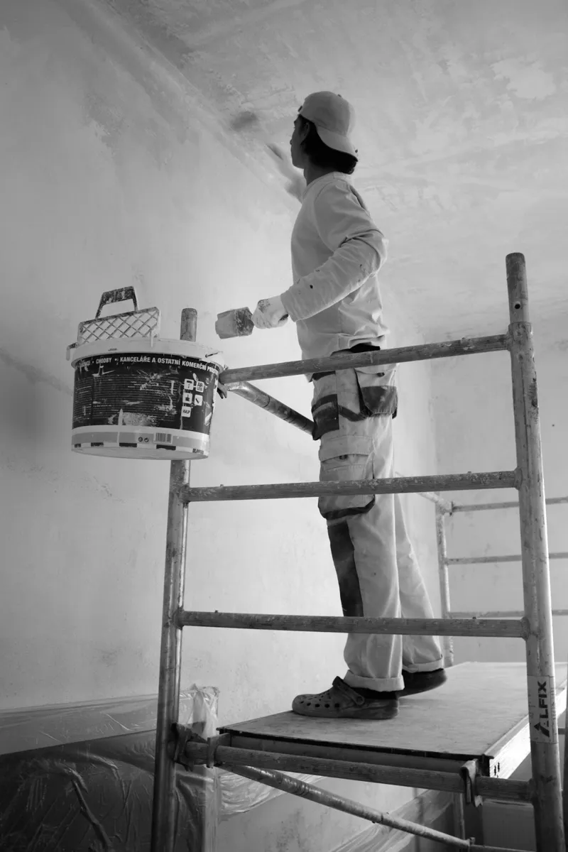 Worker on scaffolding doing wall and ceiling paint touch-up